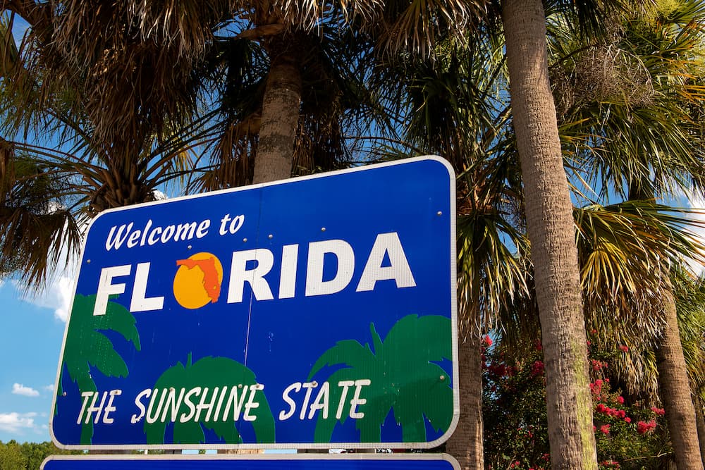A Welcome to Florida road sign sits on a sunny day as Fluent explains the process for using your MMJ card in Florida