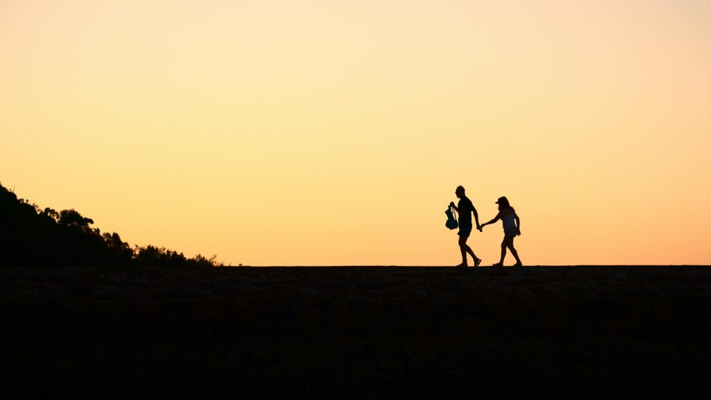 a silhouette of a couple walking on a rock wall